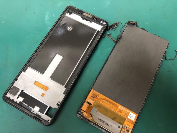 スマホの壊れた画面が外された状態で置かれています