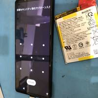 Xperia1Ⅲ(エクスペリアワンマークスリー)の修復後、画面が表示されている本体と、取り出した古いバッテリーの写真です!